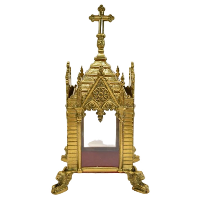 A traditional Gothic style brass relic shrine with a polished finish, cross on top. Clear glass on all four sides. Removable top to display your relics.