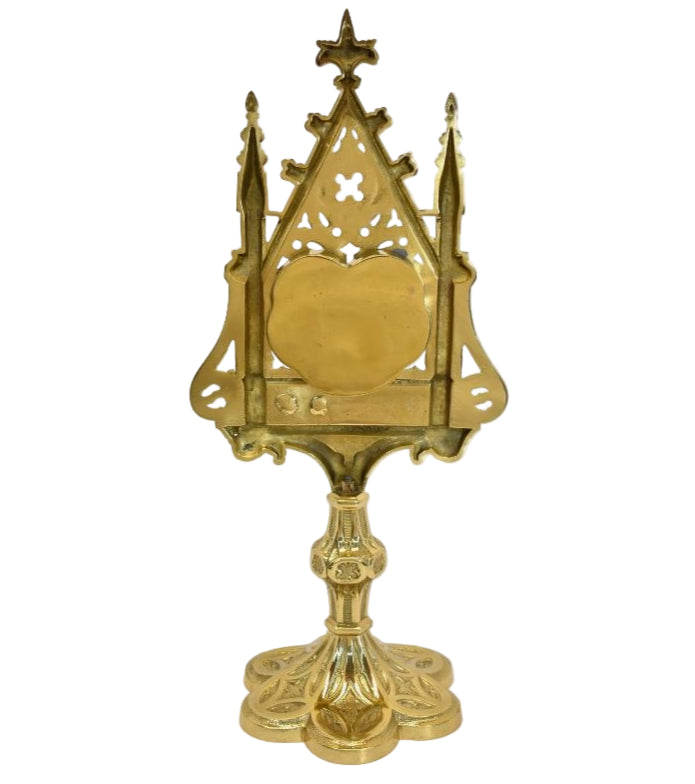 A polished brass and lacquered Gothic reliquary with a relic compartment and a heart-shaped glass opening in the center. Removable back door to house your relic.