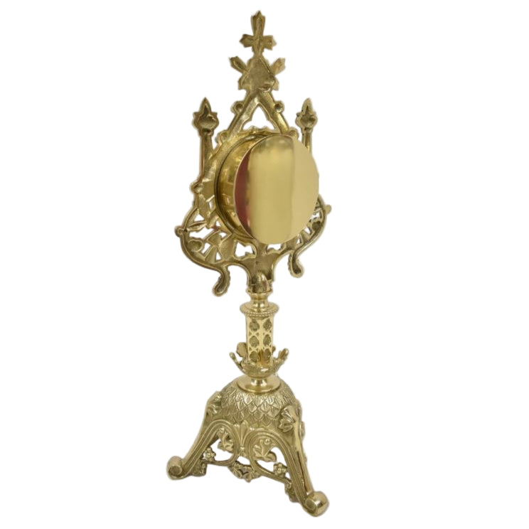 A polished brass and lacquered French style reliquary with a large round front glass and a relic compartment, displayed on a triangular base.