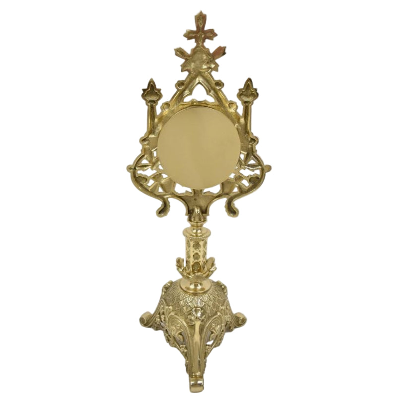 A polished brass and lacquered French style reliquary with a large round front glass and a relic compartment, displayed on a triangular base.