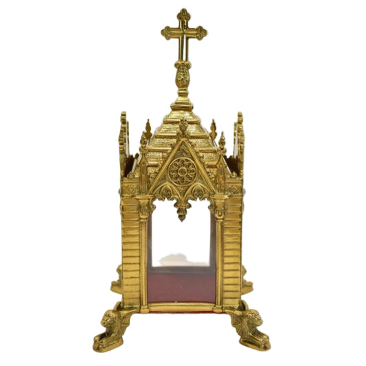A traditional Gothic style brass relic shrine with a polished finish, cross on top. Clear glass on all four sides. Removable top to display your relics.
