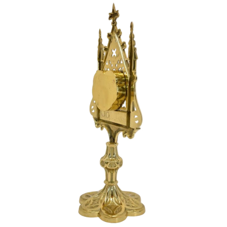 A polished brass and lacquered Gothic reliquary with a relic compartment and a heart-shaped glass opening in the center. Removable back door to house your relic.