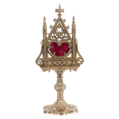 A polished brass and lacquered Gothic reliquary with a relic compartment and a heart-shaped glass opening in the center. Removable back door to house your relic.